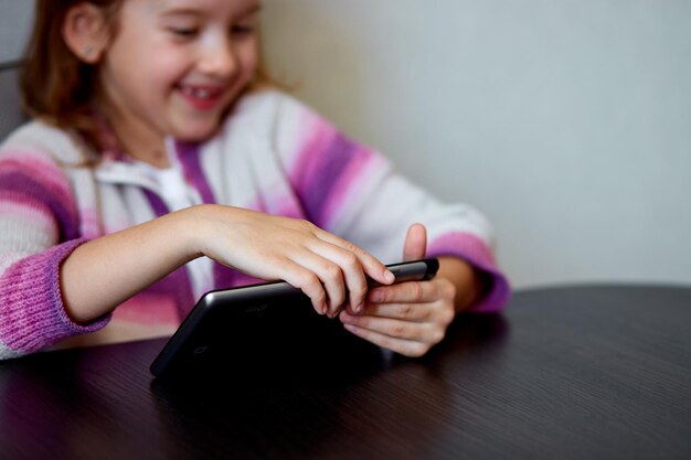 Niña sonriendo mientras se dedica a la tableta digital en el interior