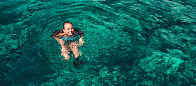 Niña sonriendo y nadando en el mar