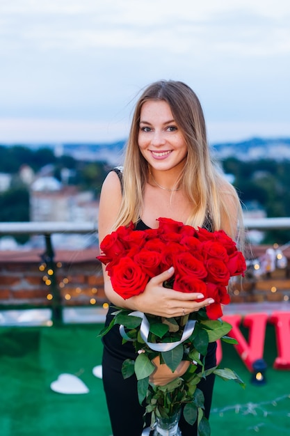 Niña sonriendo y sosteniendo un ramo de rosas rojas