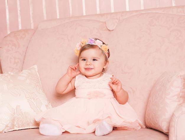 Niña sonriente de 1 año vistiendo un vestido rosa de moda