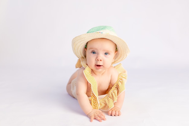 Niña sonriente de 6 meses en traje de baño y sombrero para el sol acostado
