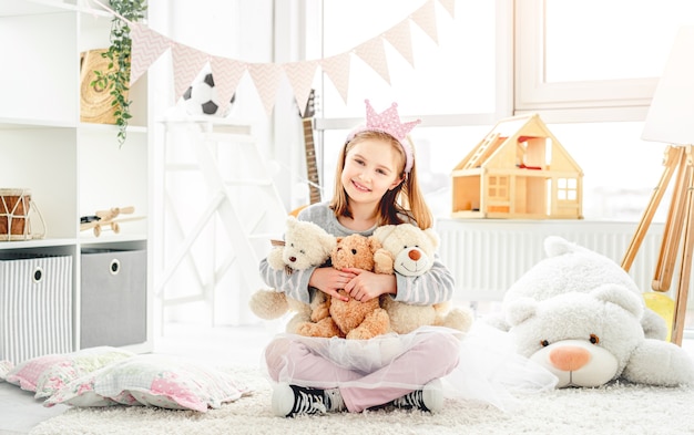 Niña sonriente abrazando osos de peluche