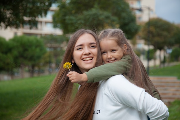 Niña sonriente abrazando a su madre en el parque