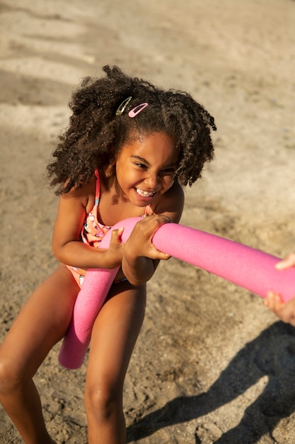 Niña sonriente de alto ángulo en la playa