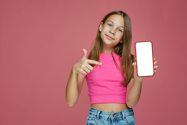 Foto niña sonriente apuntando al teléfono con pantalla en blanco anunciar la oferta de la tienda en línea para bebés o