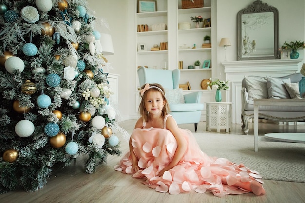 Niña sonriente con árbol de Navidad en casa