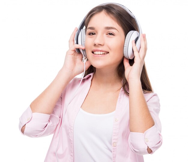 Niña sonriente con auriculares está escuchando una música.