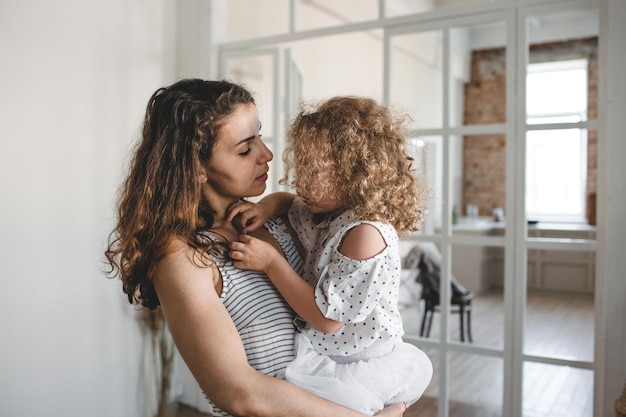 Una niña sonriente en los brazos de su madre Familia feliz y el concepto de amor interior de la casa