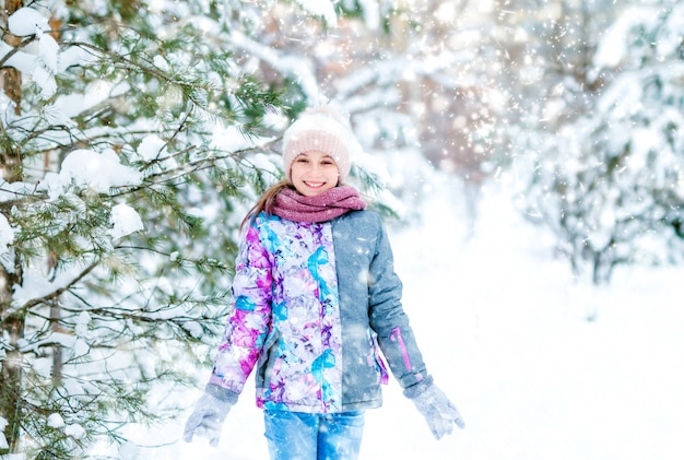 Niña sonriente caminando en bosque de invierno