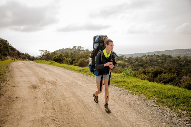 Niña sonriente caminando por el sendero verde con mochila de senderismo