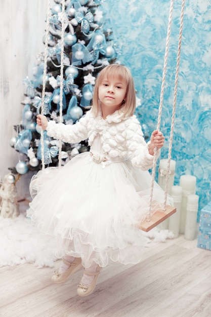 Niña sonriente cerca de árbol de Navidad