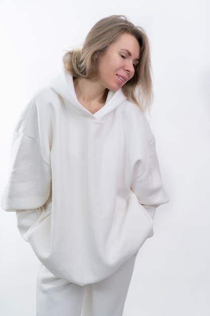 Foto niña sonriente en chándal blanco posando sobre fondo blanco.