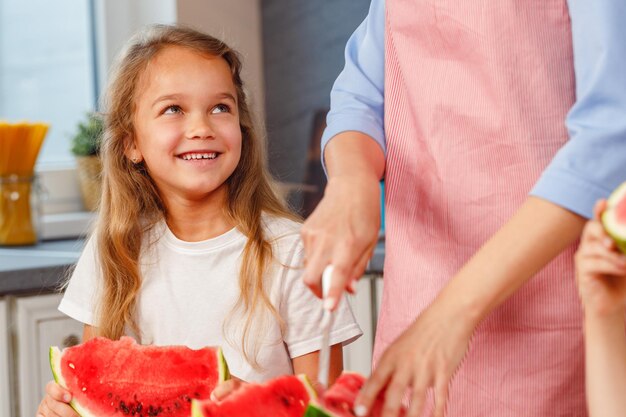 Niña sonriente comiendo una rodaja de sandía en la cocina