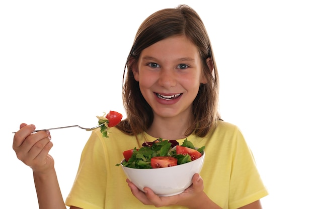 Niña sonriente comiendo sano con ensalada fresca