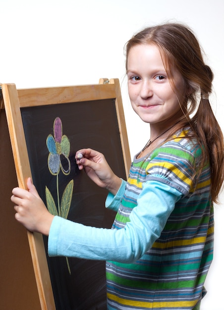 Niña sonriente dibujo con tiza sobre un caballete de madera