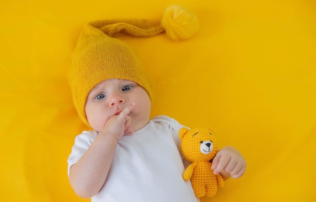 una niña sonriente se va a dormir con un oso de peluche en un fondo amarillo