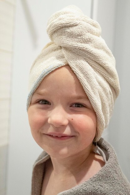 Niña sonriente envuelta en toalla de baño y toalla