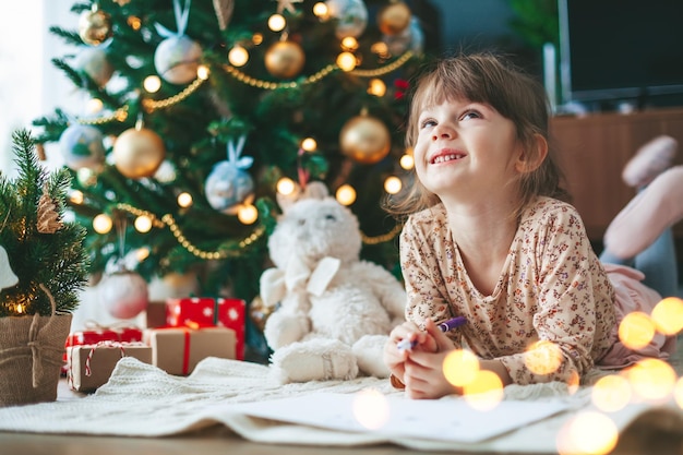 Niña sonriente escribiendo una carta a Santa Claus