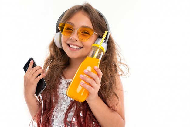 Niña sonriente escucha música en el teléfono inteligente