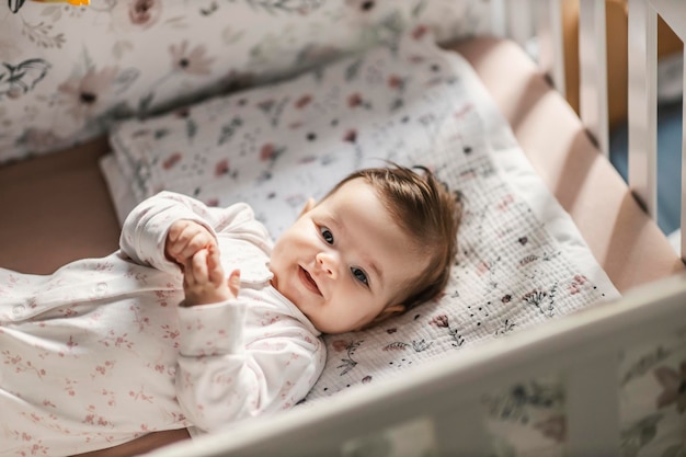 Una niña sonriente está mirando a la cámara mientras está acostada en su cuna