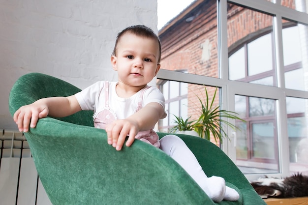 Una niña sonriente está sentada en una silla en casa Emociones positivas