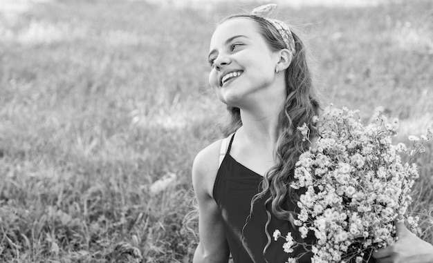 Niña sonriente feliz cosechando flores de manzanilla orgánica