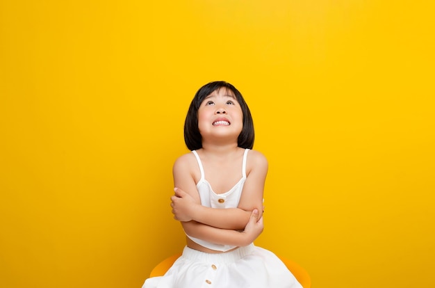 Niña sonriente una foto de una niña feliz sentada y sonriendo en una foto de sonrisa de fondo amarillo