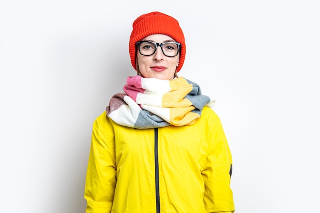 Niña sonriente con gafas, con una chaqueta amarilla en un fondo claro.