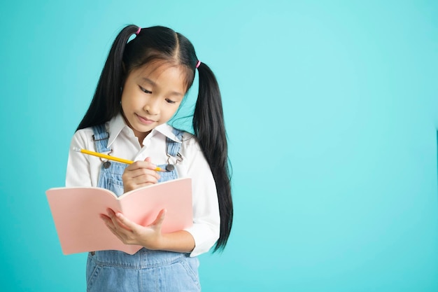 Niña sonriente con gafas y concepto de educación sosteniendo libros de texto leyendo, pensando y escribiendo