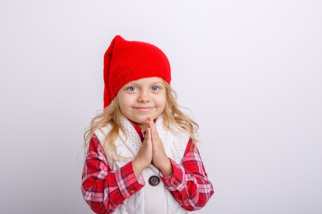 Una niña sonriente con un gorro de Papá Noel cruzó los brazos frente a ella, completamente aislada sobre un fondo blanco.