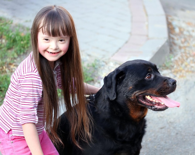 Niña sonriente con un gran perro negro