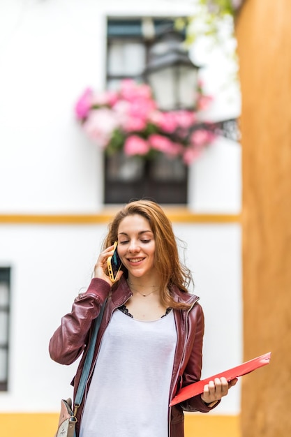 Niña sonriente hablando por su teléfono inteligente mientras estudiaba en el extranjero en sevilla, españa