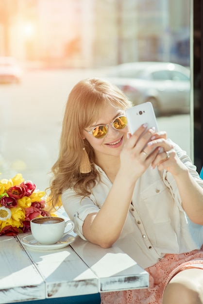 Niña sonriente hace un selfie sentado en la terraza del café