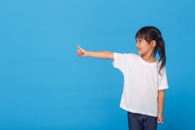 Niña sonriente haciendo aceptar firmar en la pared azul