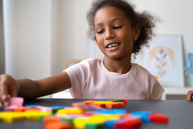 Foto niña sonriente haciendo rompecabezas en la mesa de tiro medio