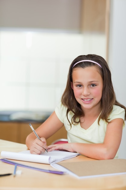 Foto niña sonriente haciendo la tarea