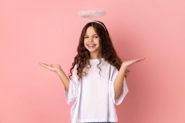 Niña sonriente con halo sobre la cabeza de pie mirando a la cámara extendió las manos a un lado