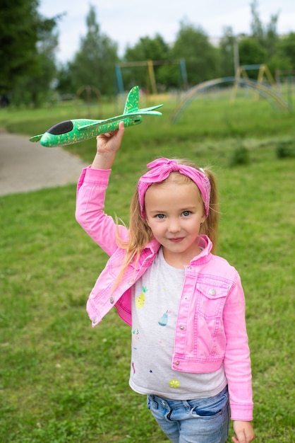 Una niña sonriente juega con un avión al aire libre.