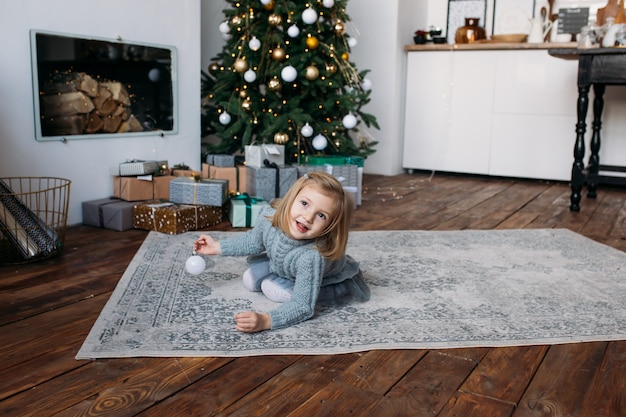 Niña sonriente jugando con decoración navideña