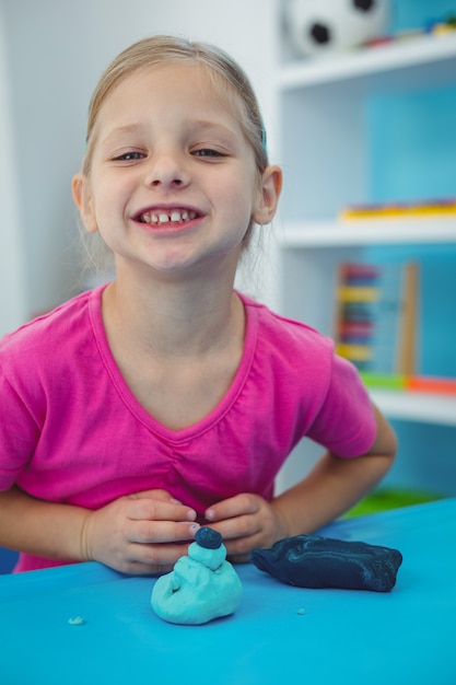 Niña sonriente jugando con plastilina