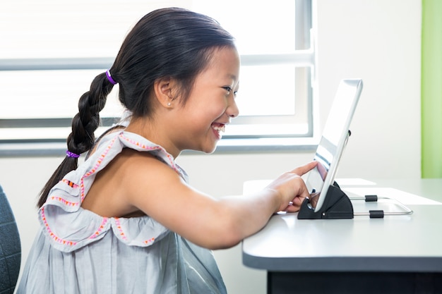 Niña sonriente con laptop en el aula