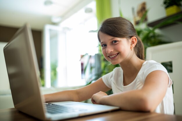 niña sonriente con laptop en la sala de estar