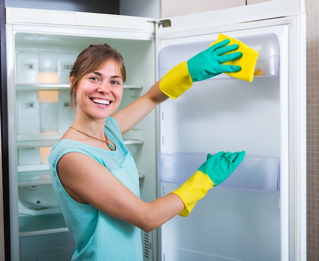 Niña sonriente limpiando el refrigerador