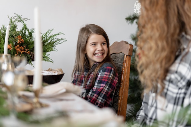 Niña sonriente con mamá desayunando en casa Navidad familiar Concepto de Navidad en casa