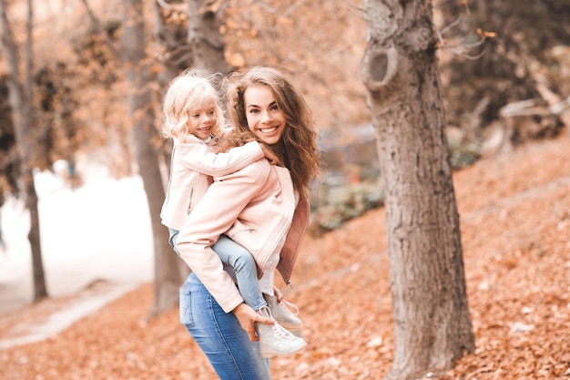 Niña sonriente en manos de la madre en el parque