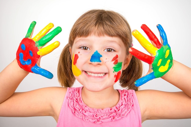 Niña sonriente con las manos pintadas con pinturas de colores