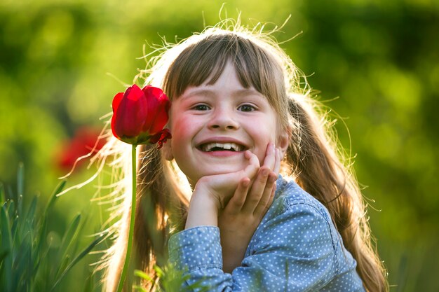 Niña sonriente niño con flor de tulipán rojo