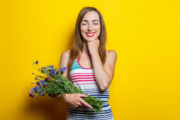 Niña sonriente con los ojos cerrados sosteniendo flores silvestres