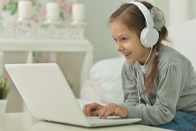 Niña sonriente con ordenador portátil en casa