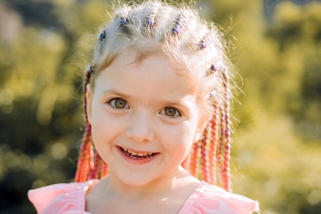 Niña sonriente con peinado rastas niño con cabello de moda al aire libre niño feliz afuera